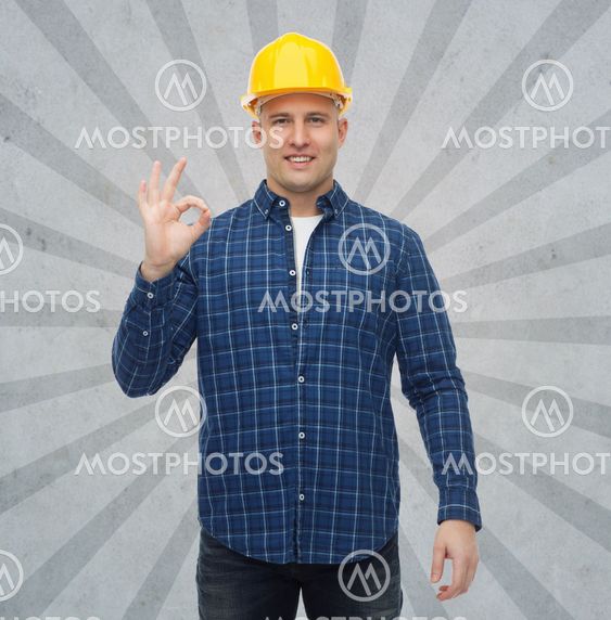 smiling male builder in helmet showing ok sign