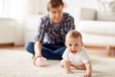 happy father with baby and piggy bank at home