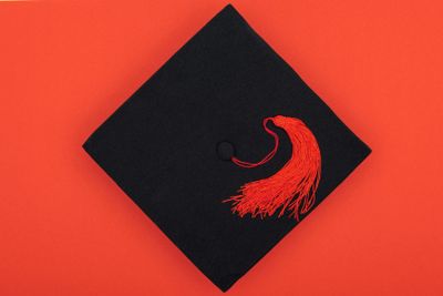 Top view of academic cap with tassel isolated on red