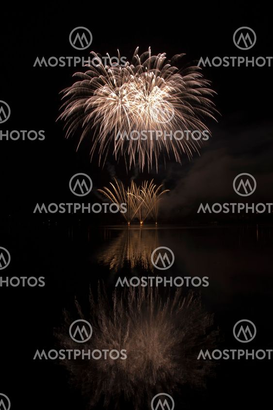 Colorful fireworks on the black sky background and water reflections