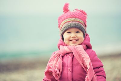 Happy baby girl in pink hat and scarf laughs