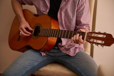 Man playing a classical guitar while sitting indoors...