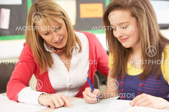 Female Teenage Student Studying In Classroom With Teacher