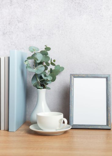 Eucalyptus branches, books, empty frame and coffee cup...