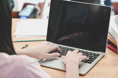 Closeup young female using laptop computer on table in...