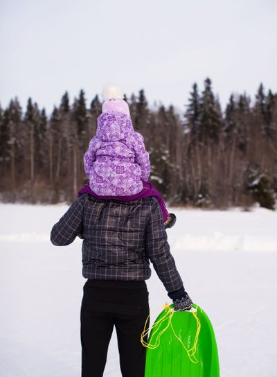 Little girl riding on dad outdoors in cold winter day