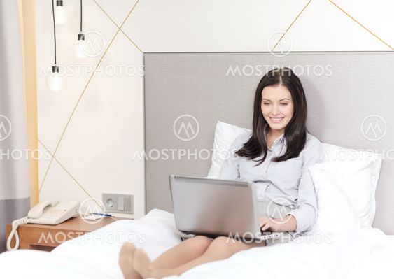 happy businesswoman with laptop in hotel room