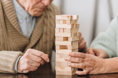 cropped view of retired couple playing jenga game at home