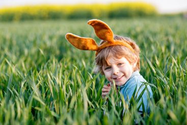 little kid boy having fun with traditional Easter egg hunt
