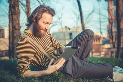 young bearded stylish handsome hipster man using tablet 
