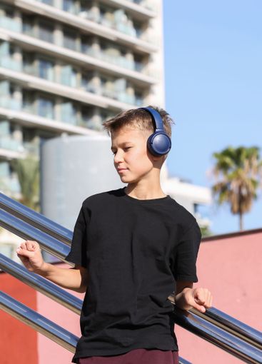 Handsome teenager standing with skateboard and listening...