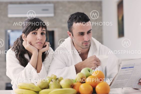 Happy couple reading the newspaper in the kitchen at breakfast