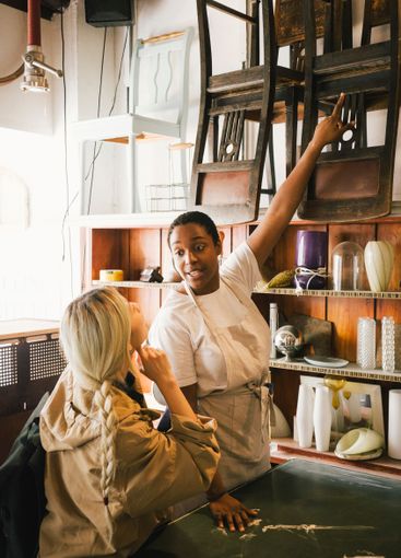 Female entrepreneur showing chairs to customer at...