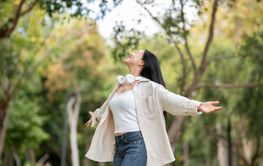 An asian woman is standing with open arms while turning...