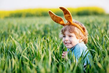 little kid boy having fun with traditional Easter egg hunt