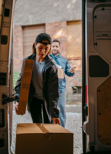 Male and female delivery coworkers unloading boxes from...