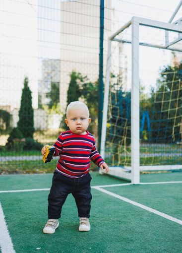 A fair-haired one-year-old boy in jeans and sneakers...