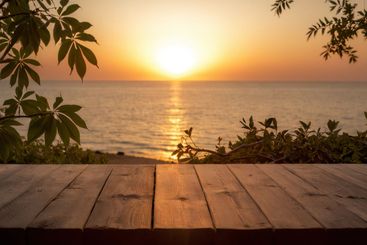 Photo of a wooden table with a view of the ocean and sunset