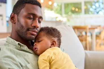 Family Shot With Father Cuddling Baby Daughter Sleeping...