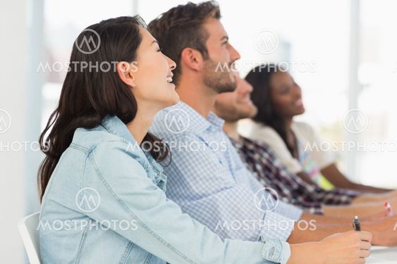 Smiling team of young designers listening at meeting