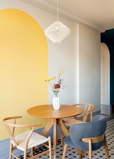 Close-up of a round wooden table with a vase of flowers....