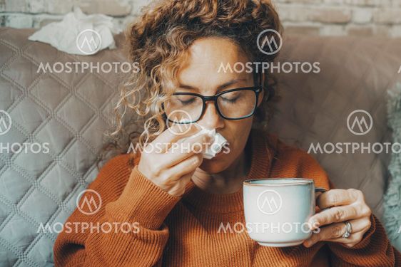 Sick woman at home blowing nose and take care of...