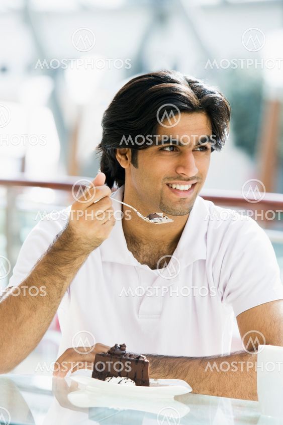 Young man eating cake in cafe