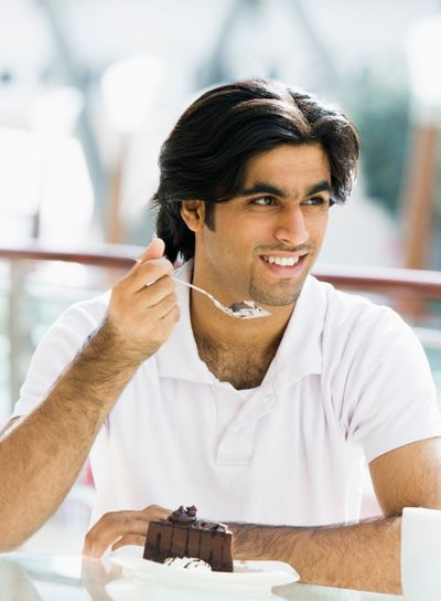 Young man eating cake in cafe