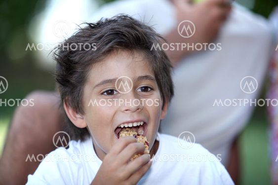 Little boy eating cereal bar outdoors