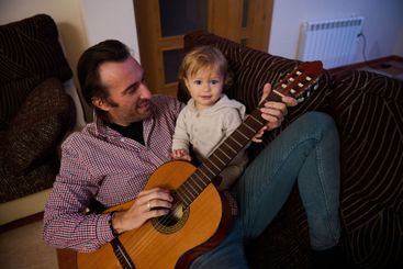 Father and child playing acoustic guitar together...