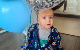 Happy smiling toddler boy sitting on floor and playing...