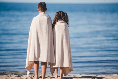 back view of boy and girl in towels standing together on...