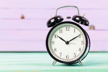 Black vintage alarm clock on wooden table