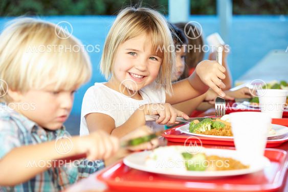 Elementary Pupils Enjoying Healthy Lunch In Cafeteria