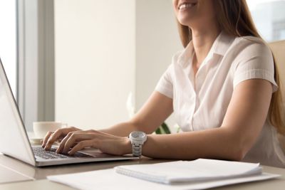 Close up photo of womans hands typing on laptop