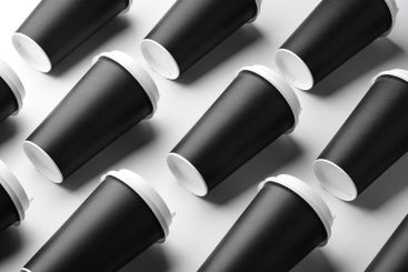 Multiple black takeaway coffee cups arranged in a...