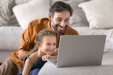 Loving father and little daughter using laptop together...