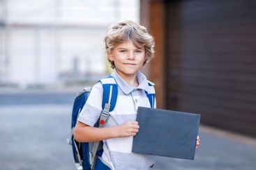 Happy little kid boy with satchel. Schoolkid on the way...