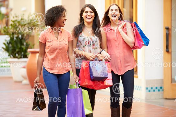 Female Friends Walking Through Mall With Shopping Bags