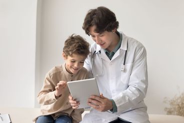 Young male doctor use tablet on meeting with little boy