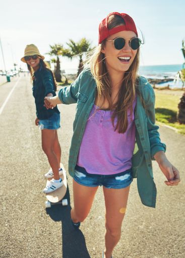 Happy, travel or women skateboarding by sea for holiday...