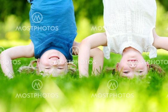 Happy children playing head over heels on green grass