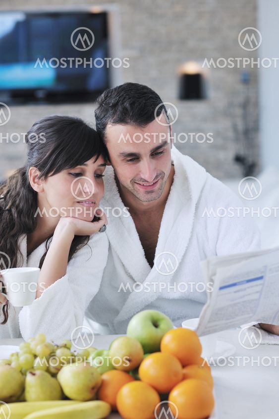 Happy couple reading the newspaper in the kitchen at breakfast