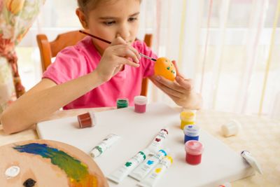 girl painting colorful eggs for Easter
