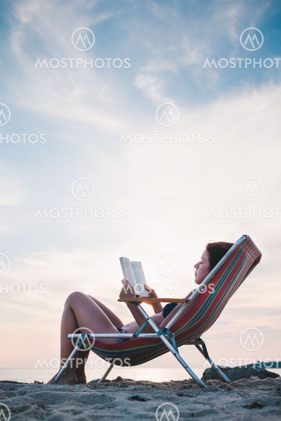 Young woman reading a book on the beach
