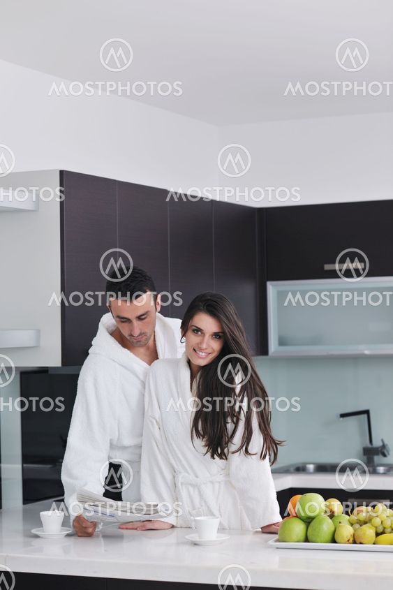 Happy couple reading the newspaper in the kitchen at breakfast
