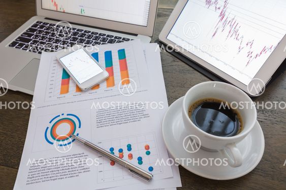 Laptop, tablet , smartphone and coffee cup with financial documents on wooden table