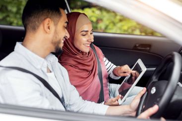 Cheerful millennial muslim female in hijab shows way on...