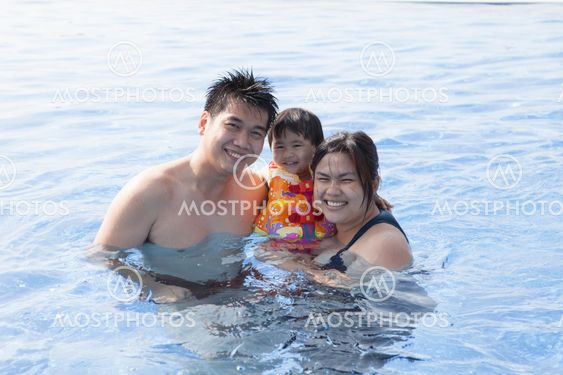 father mather and dauther happiness time in swimming pool smiling to camera