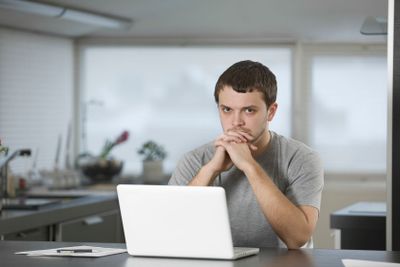 Man With Laptop Sitting At Kitchen Counter